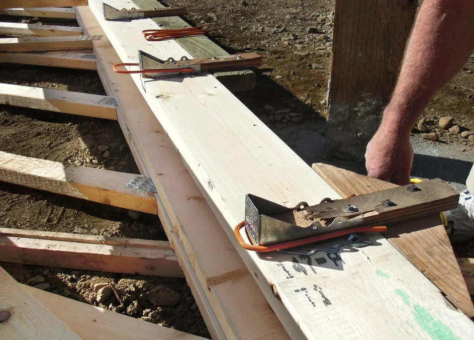 Hands positioning framing lumber on a new deck frame